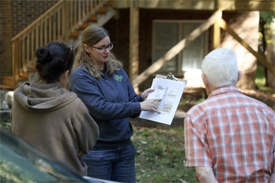 Stormwater staff member pointing to information on clipboard to a family