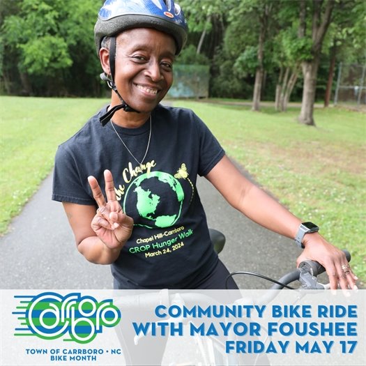 Mayor Foushee giving a peace sign, wearing a helmet and riding a bike