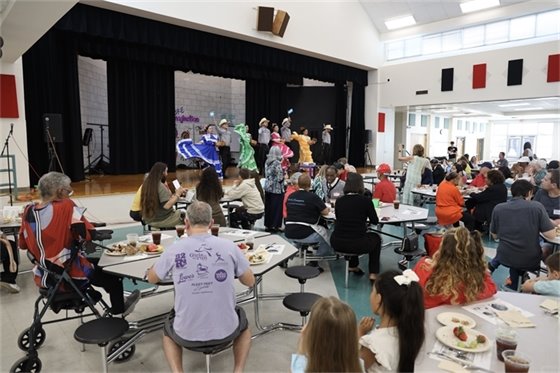 Scene at Community Dinner with dancers on stage 