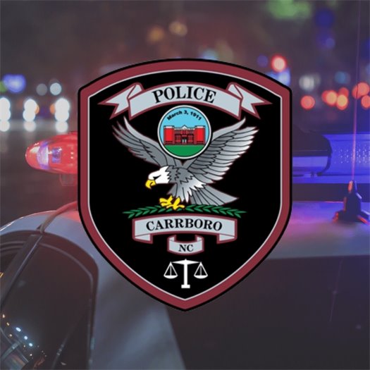 Carrboro Police Patch in front of a police car with flashing lights at night
